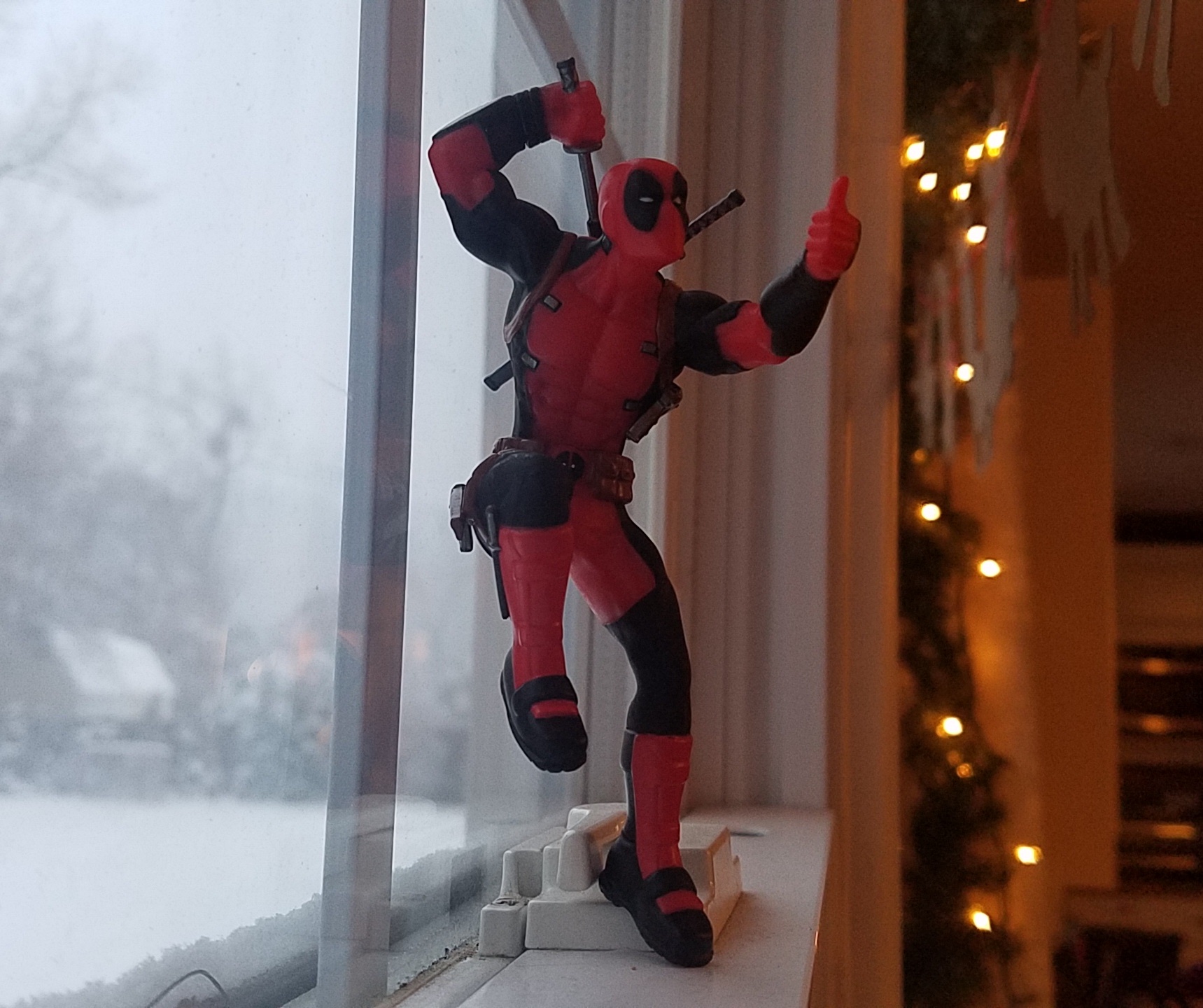 Deadpool figure on the windowsill giving a thumbs up
